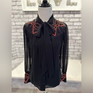 Black chiffon shirt with bright orange design embellishments.